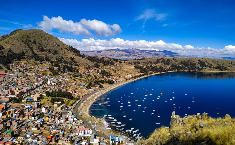 Ciudad en la orilla con muchos botes de diferentes tamaños en el lago Titicaca con Exploor Peru