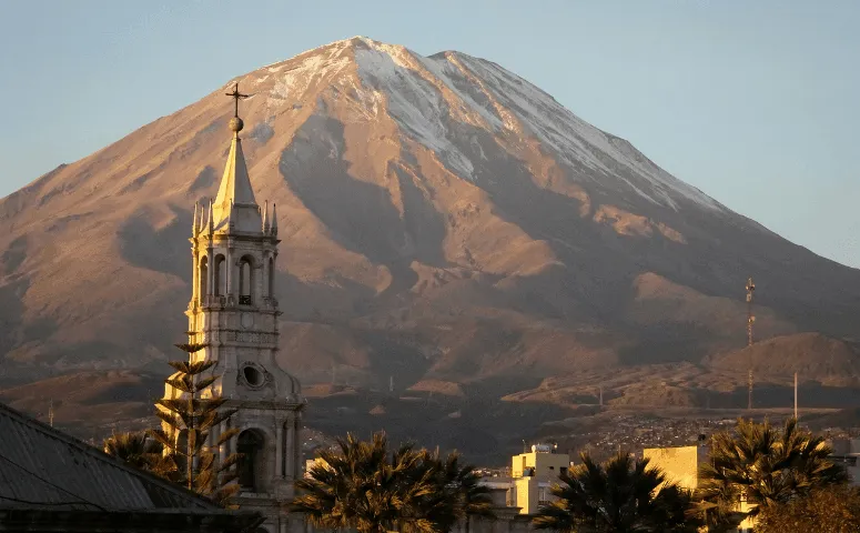 cathedral and other buildings in front of volcano