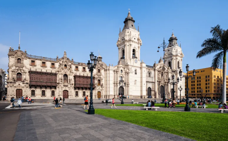plaza principal de lima con gran edificio que esta rodeado de viajeros