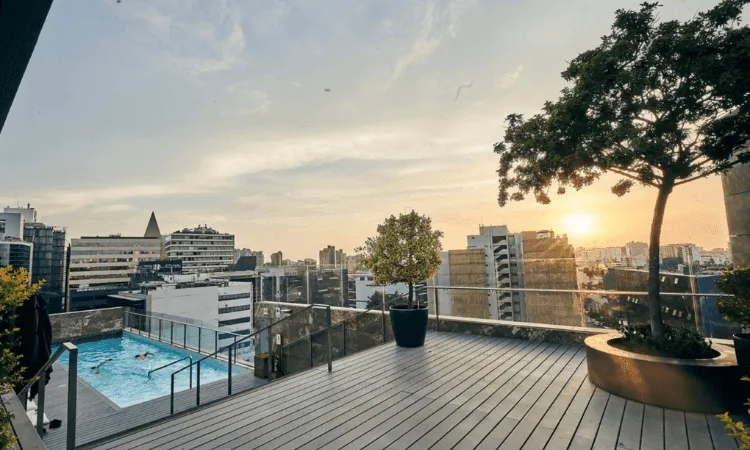 vista de la puesta de sol desde la azotea con piscina y edificios al fondo