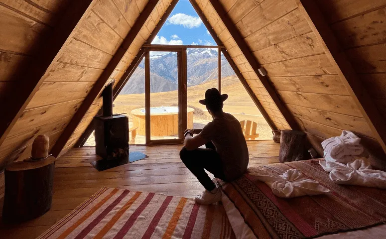 traveler sitting inside of the lodge and enjoying view on hot tub and andes