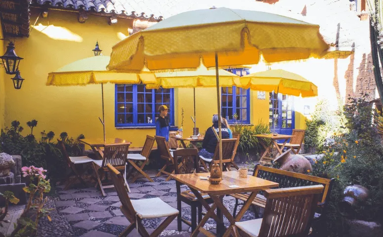 Yellow house wall and travelers are sitting at a table Lake Titicaca Peru with Exploor Peru