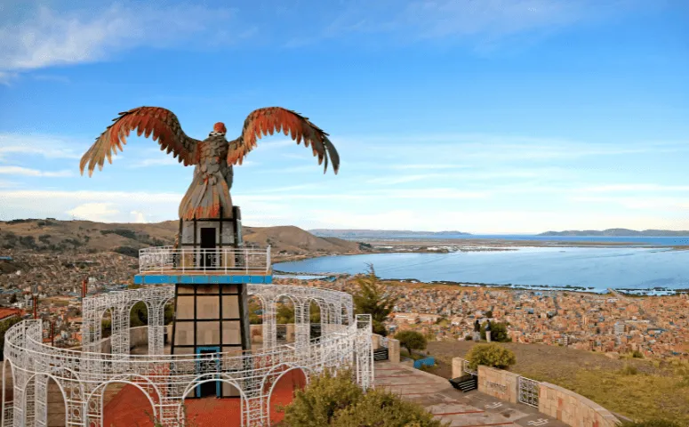 Statue of a condor and view over the entire city of Puno and lake titicaca with Exploor Peru